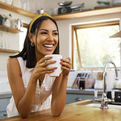 Woman smiling while drinking coffee in kitchen