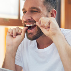 Man flossing his teeth in bathroom