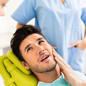 Man in dental chair holding jaw