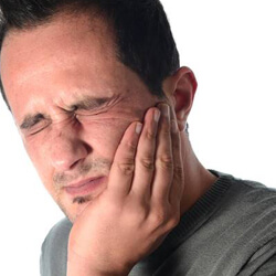 Man holding jaw in pain