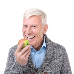 Man about to bite into an apple while wearing a sweater