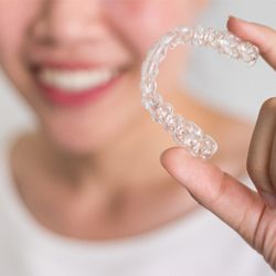 A woman holding an Invisalign aligner