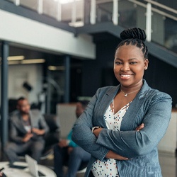 A young businesswoman smiles proudly while her colleagues work together on a project