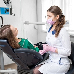 A female dentist sitting next to a patient answering their questions about a particular dental emergency