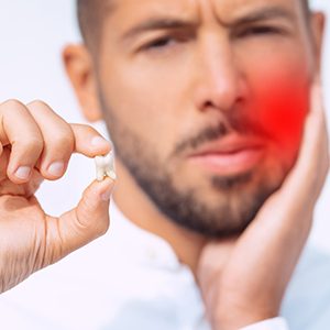 a person holding their tooth and face