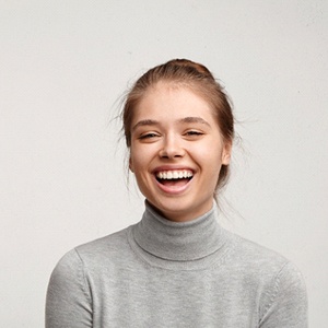 A young female wearing a gray sweater smiles after addressing her gummy smile in Homer Glen