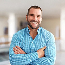 Smiling man with blue shirt crossing his arms