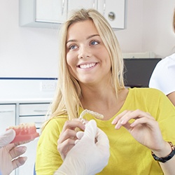 Smiling woman holding Invisalign tray