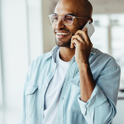 Man with glasses smiling while talking on phone
