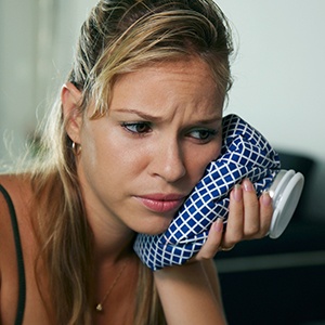 Woman holding ice pack to cheek