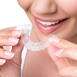 A woman holding an Invisalign aligner