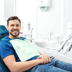 Man sitting in a dental chair next to dental instruments
