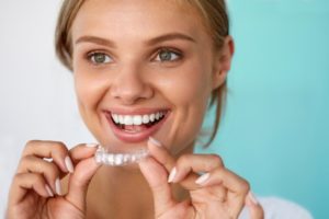 A woman holding a clear aligner.