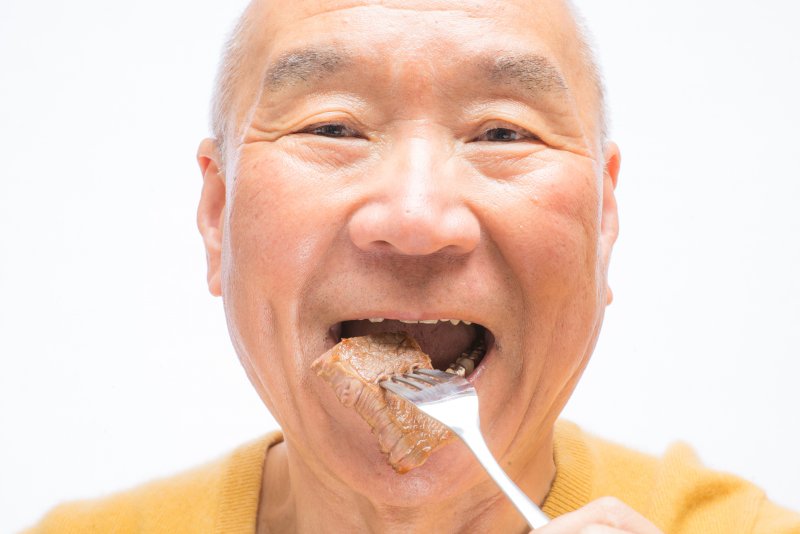 older man eating steak